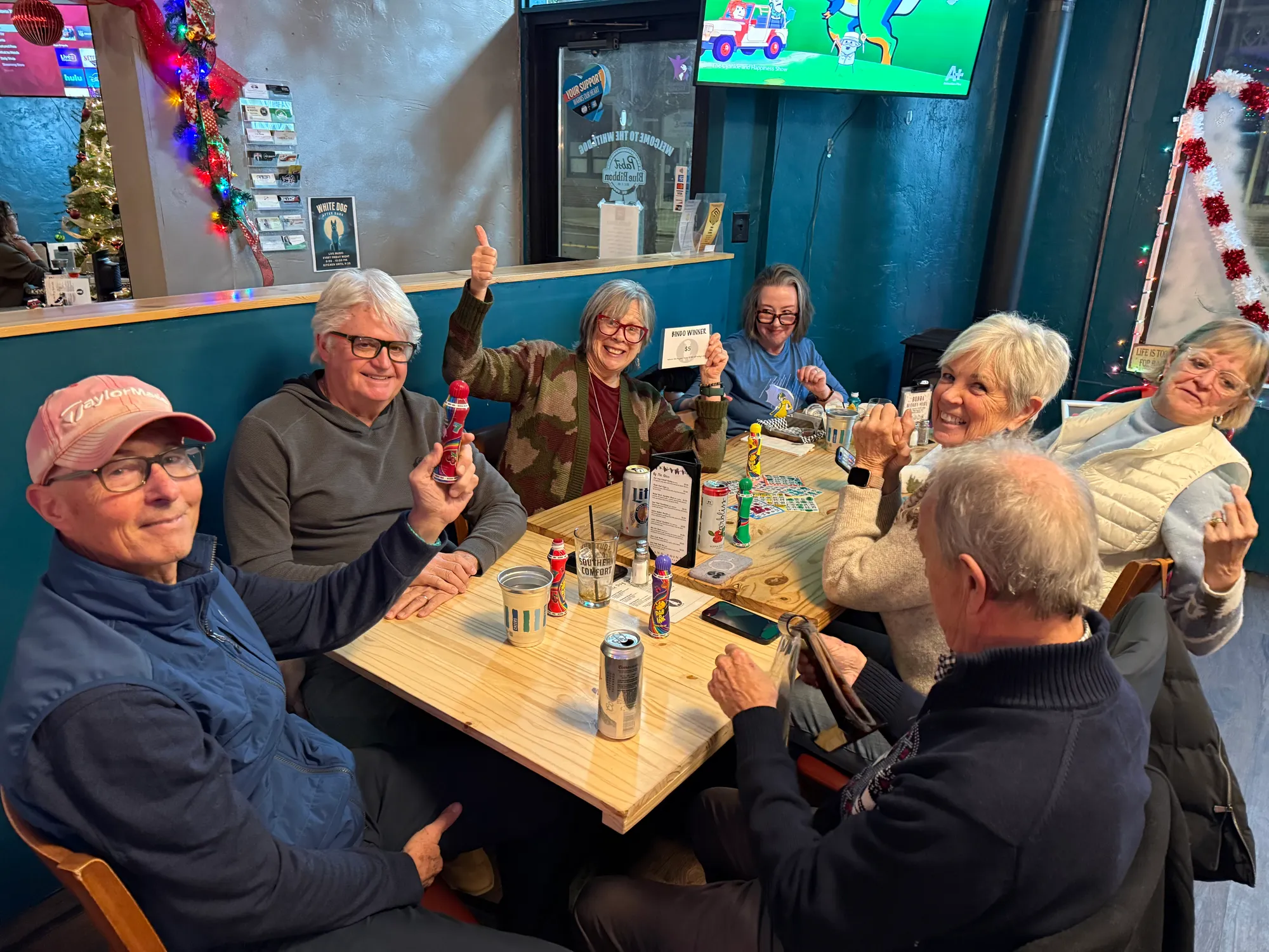 Guests gathered around a table with bingo cards and daubers on bingo night, holiday decorations behind