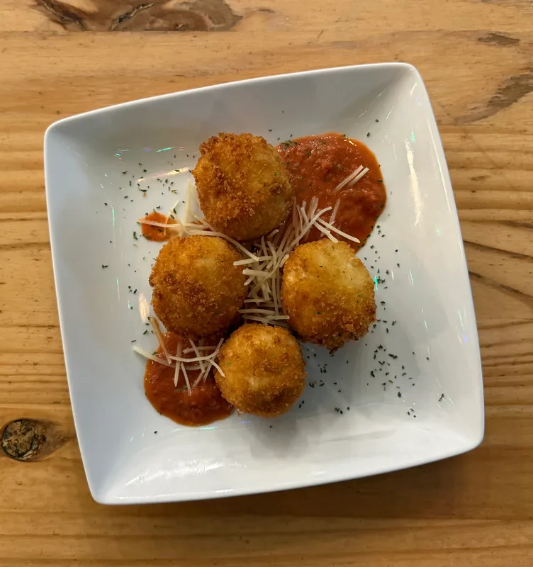 Four crispy arancini over marinara with shaved parmesan