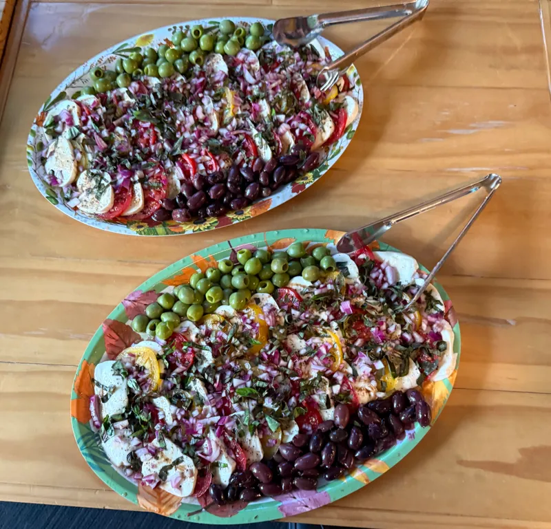 Two platters of caprese — fresh mozzarella, tomato, red onion and basil with green and kalamata olives