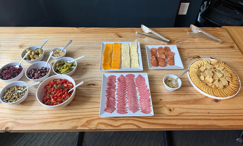The full charcuterie-style salad bar laid out on the table with cheeses, cured meats, crackers, and bowls of toppings