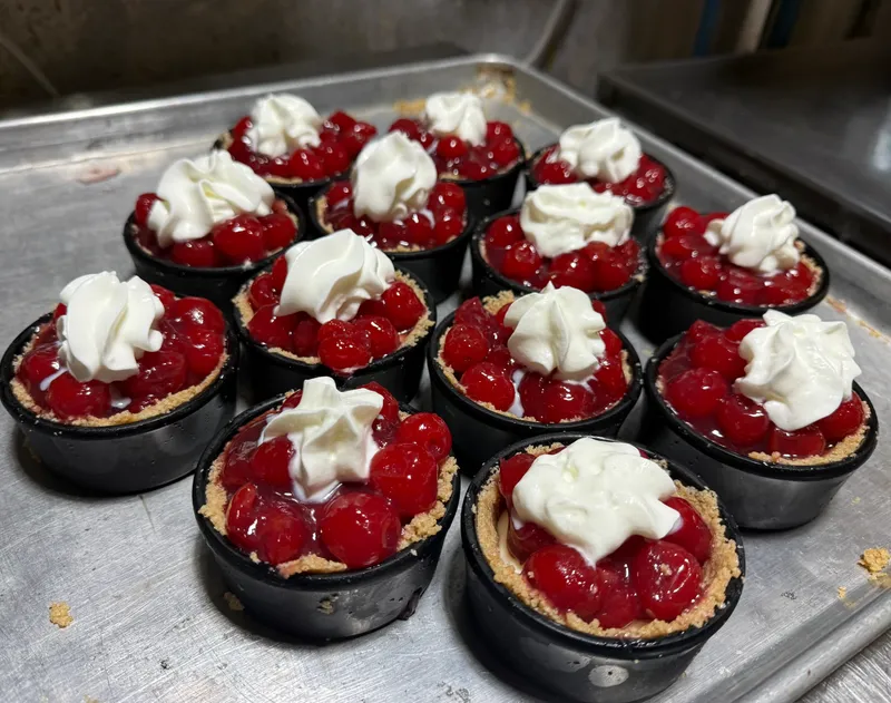 A tray of individual cherry tortes topped with whipped cream