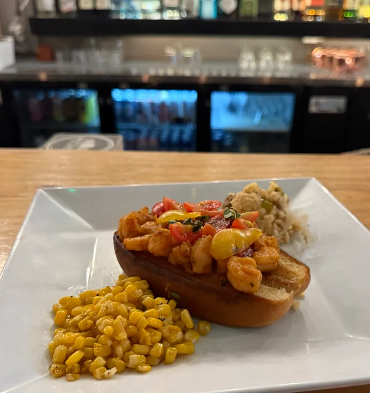 Shrimp po'boy on a toasted roll with roasted sweet corn and Cajun rice